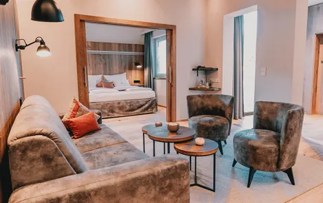 Birnhorn Moderne Hotelsuite mit gemütlicher Lounge, Samtmöbeln und Blick ins Schlafzimmer